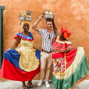 Colorful traditional dress and fruit vendors pose with a tourist in Cartagena, Colombia.